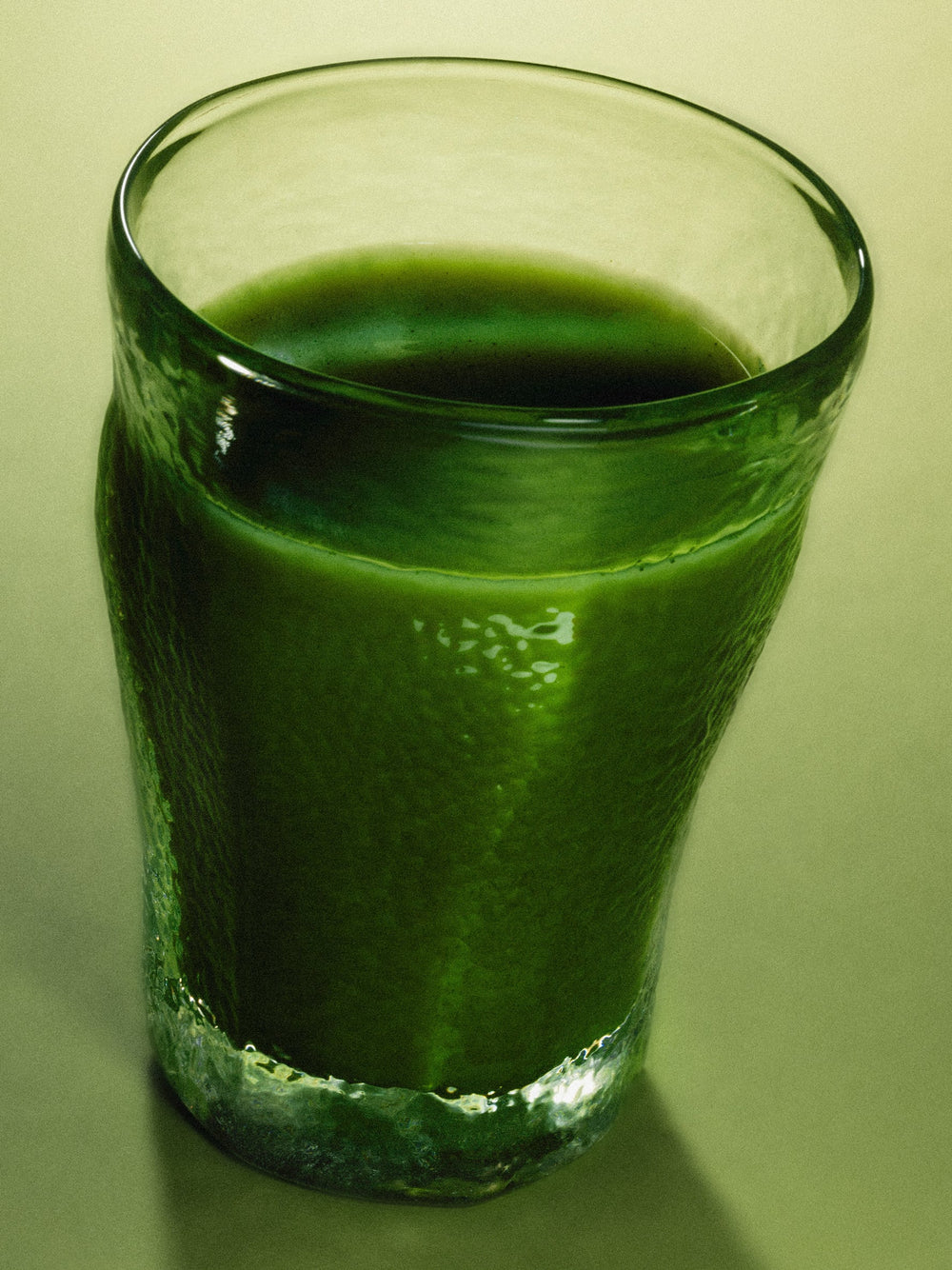 Close-up of green cardamom pods arranged in a rectangle with a rind of lime on top. The background is grey.